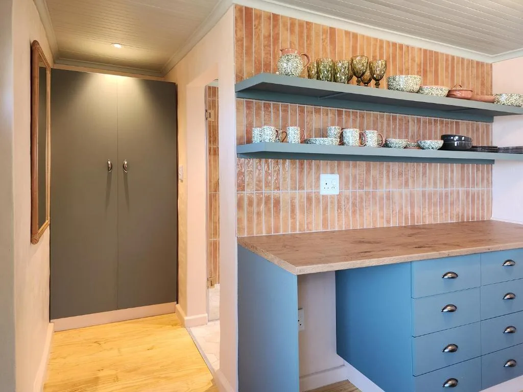 Modern kitchen with blue cabinetry, wooden countertop, and open shelving displaying dishware