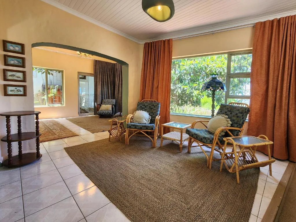 Spacious lounge with wicker chairs, large windows, and garden views