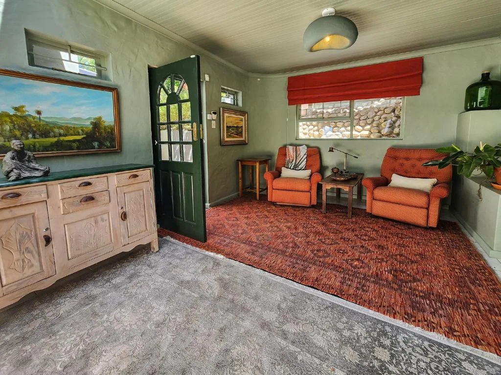 Spacious living room with orange armchairs, wooden furniture, and scenic artwork