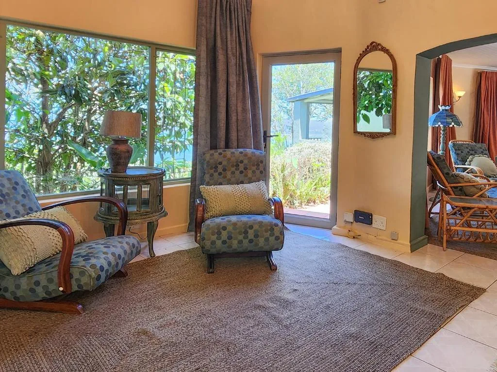 Bright lounge with patterned armchairs, side table, and garden views