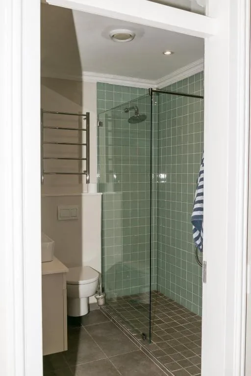 Modern bathroom with green tile shower enclosure and toilet