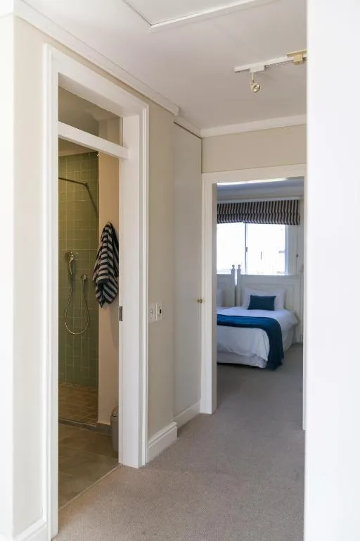 Ensuite bathroom with green tile shower and striped towel hanging