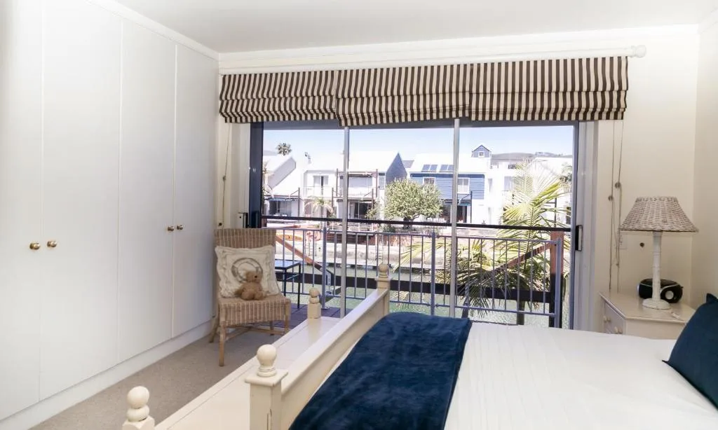 Bright bedroom with double bed, balcony doors overlooking town and waterfront views