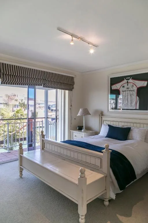 Bright bedroom with white wooden bed and ocean view balcony access