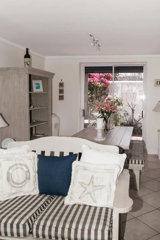 Bright bedroom with white bed, striped sofa, and garden view doors