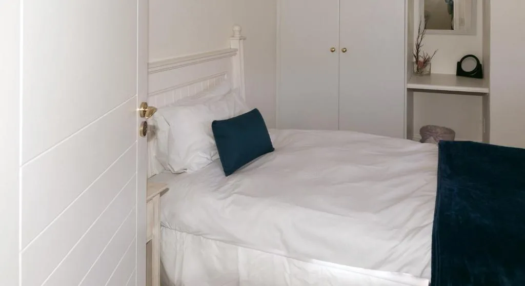 Bright bedroom with white bedding, navy accent pillows, and built-in storage