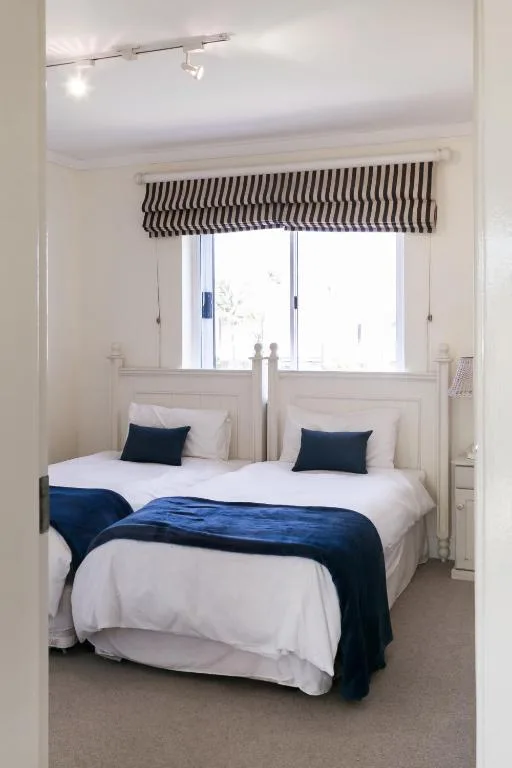 Bright bedroom with twin beds, navy accents, and striped Roman blind