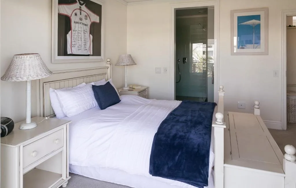Bright bedroom with white bed, navy accents, and ensuite bathroom access