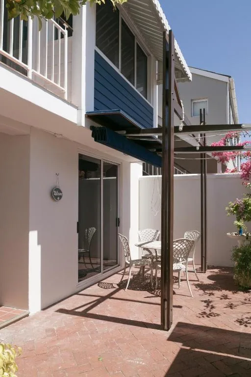 Shaded patio area with metal chairs and pergola overlooking water