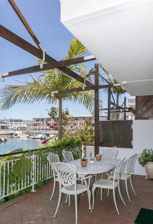 Waterfront deck with dining table, pergola, and lagoon views