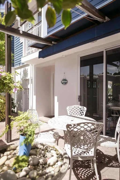 Shaded patio area with white lattice chairs and round table overlooking water