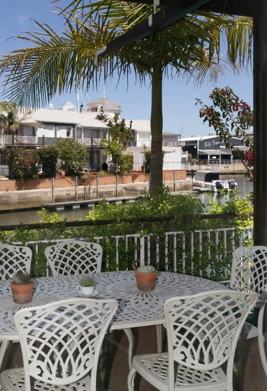 Outdoor dining table with white chairs overlooking waterfront canal