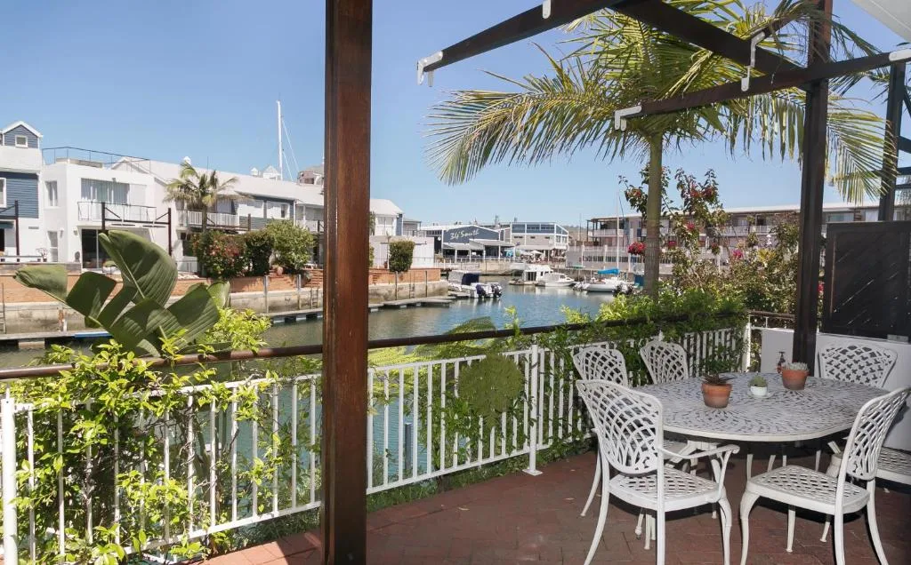 Waterfront deck with dining table overlooking Knysna lagoon and boats