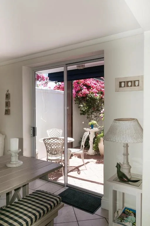 Patio area with flowering bougainvillea, white chairs, and garden views