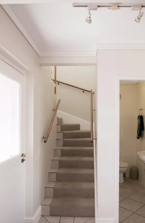 Staircase with wooden handrail and track lighting in bright hallway