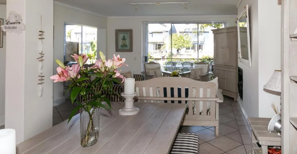 Bright open-plan living area with dining table and pink flowers in vase