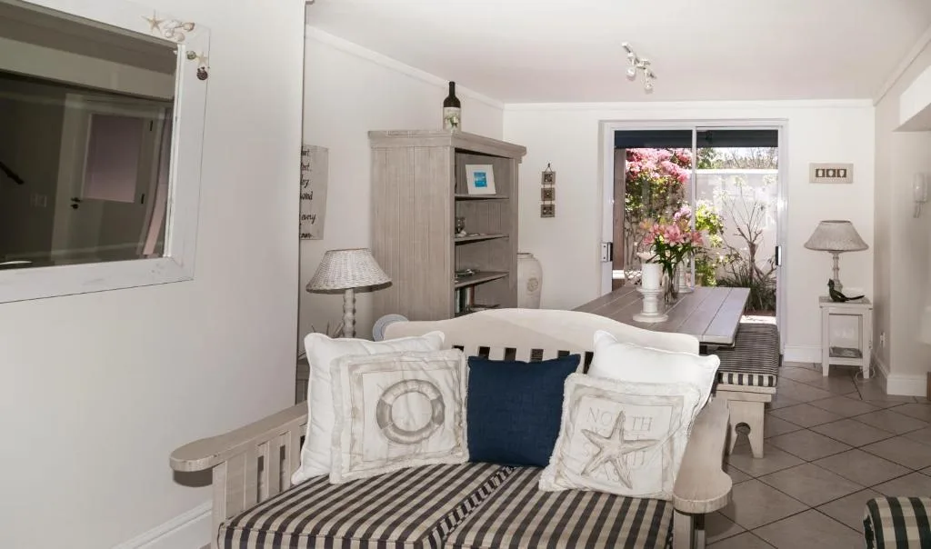 Bright lounge with striped sofa, coastal decor, and garden view through doors