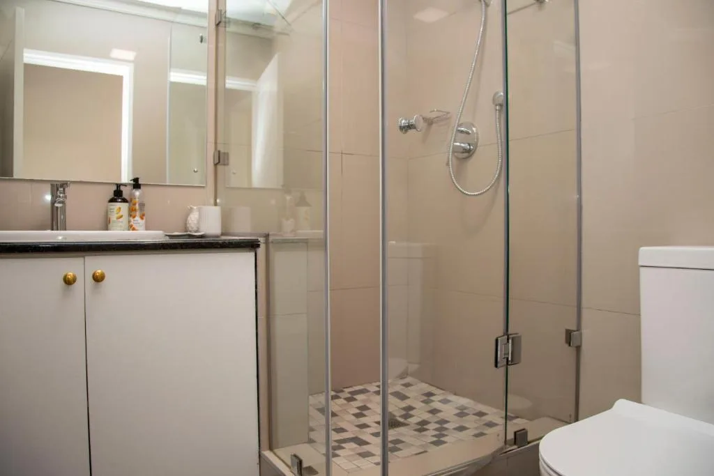 Modern bathroom with walk-in shower, vanity sink, and brass fixtures