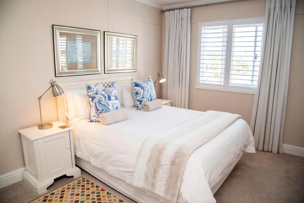 Bright bedroom with queen bed, blue patterned pillows, and shuttered windows