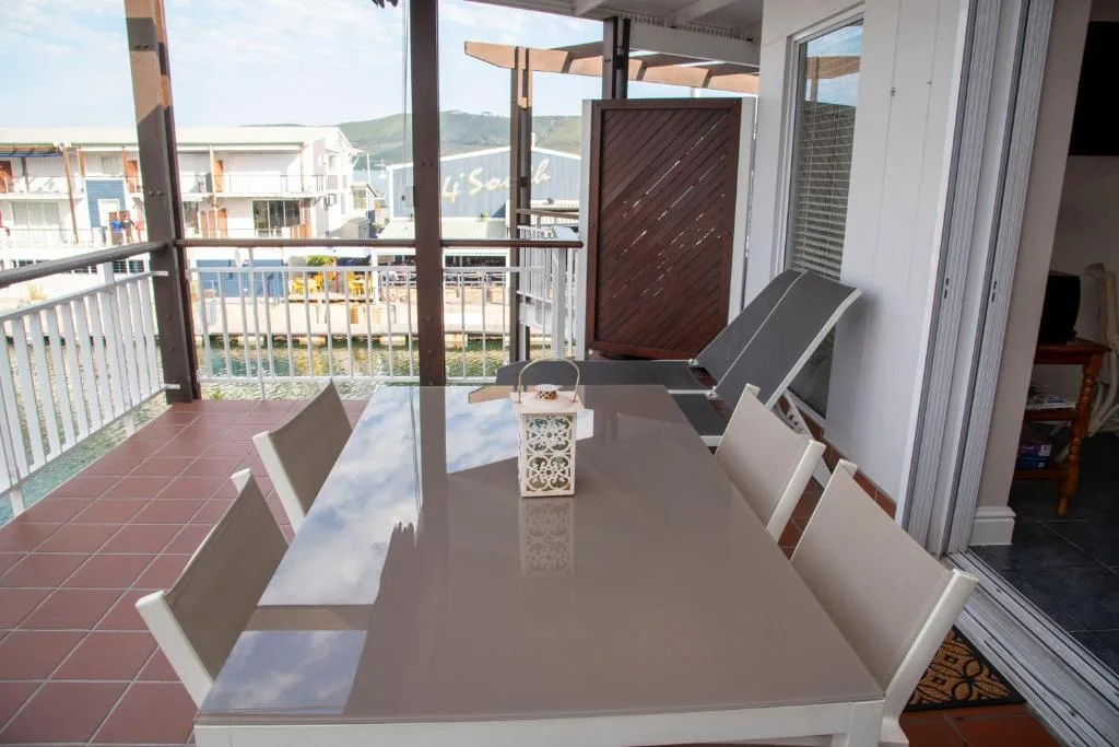Covered deck with dining table overlooking Knysna waterfront and mountains