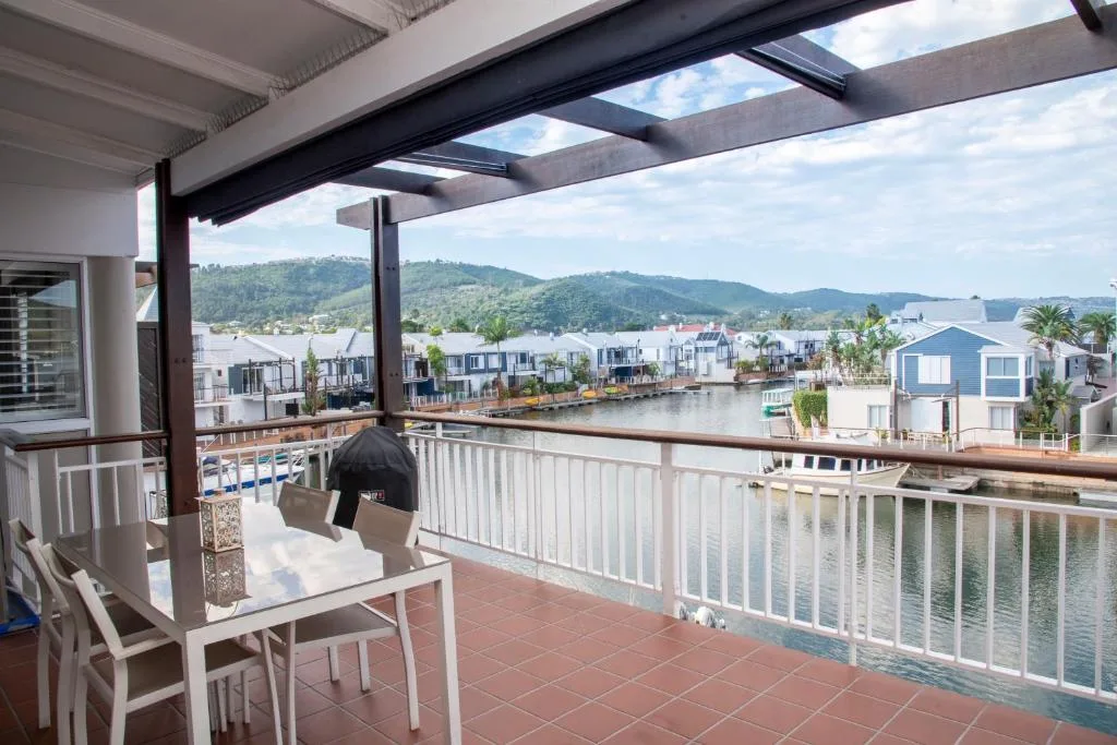 Waterfront deck with table, chairs, and scenic lagoon and mountain views