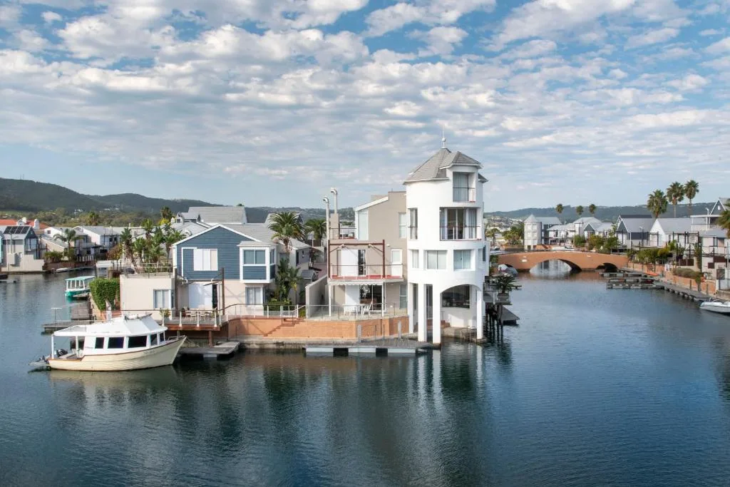 Waterfront property with distinctive white tower, wooden deck, moored boat