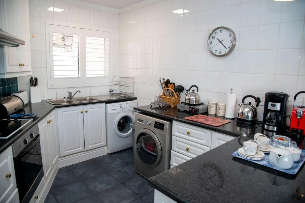 Modern white kitchen with stainless appliances and black countertops