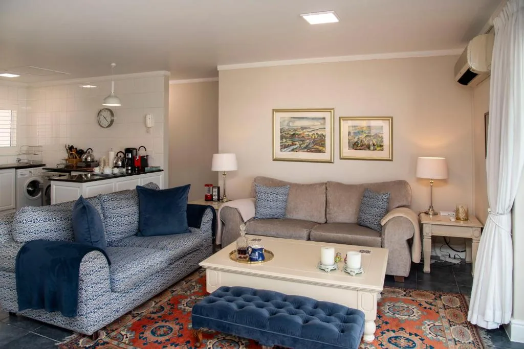 Open-plan lounge with gray sofa, patterned armchair, and kitchen visible beyond