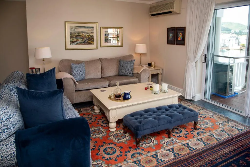 Elegant lounge with sofa, armchairs, and waterfront views through glass doors