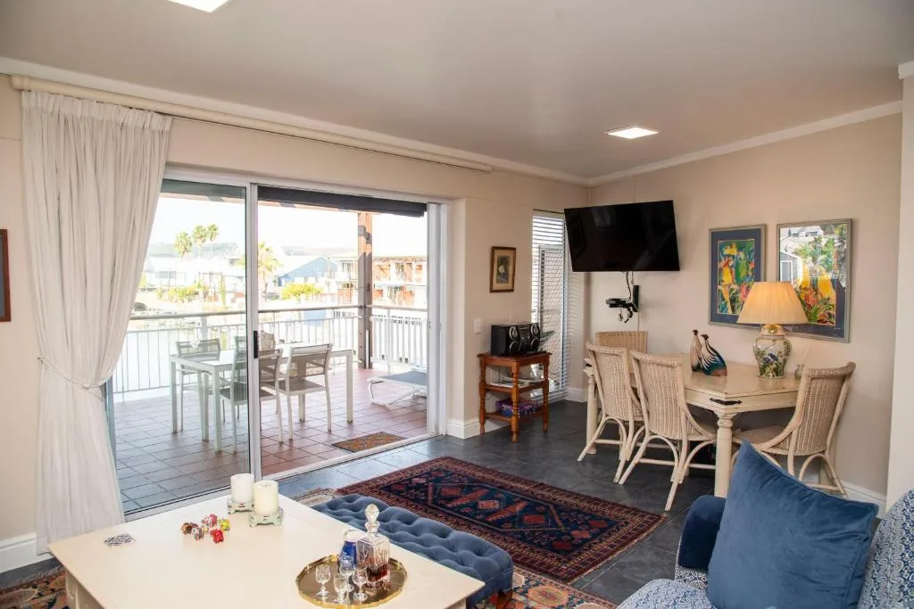 Open-plan lounge with sofa, dining area, and deck views