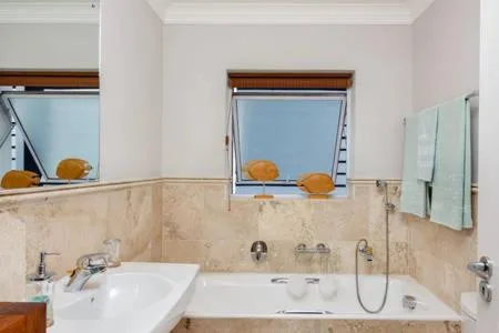 Modern bathroom with dual sinks, marble vanity, and bright windows