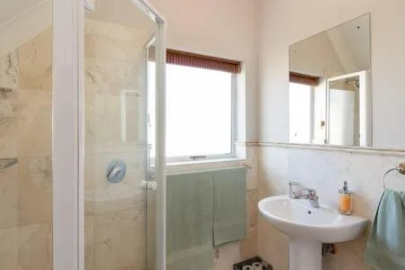 Bright bathroom with shower enclosure, pedestal sink, and window