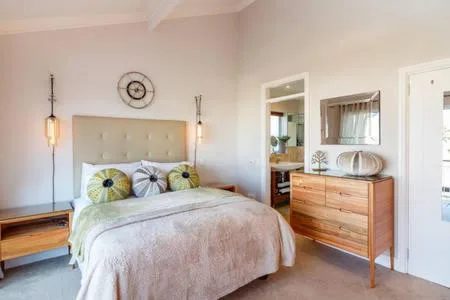 Bright bedroom with upholstered headboard, pendant lighting, and wooden dresser