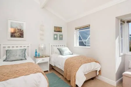 Twin bedroom with white headboards and coastal artwork on walls