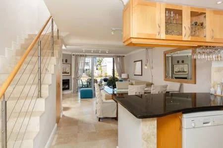 Modern kitchen with black countertop and wooden cabinetry overlooking lounge