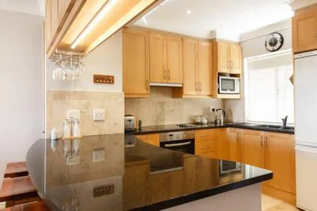 Modern kitchen with wooden cabinetry, dark countertops, and built-in appliances