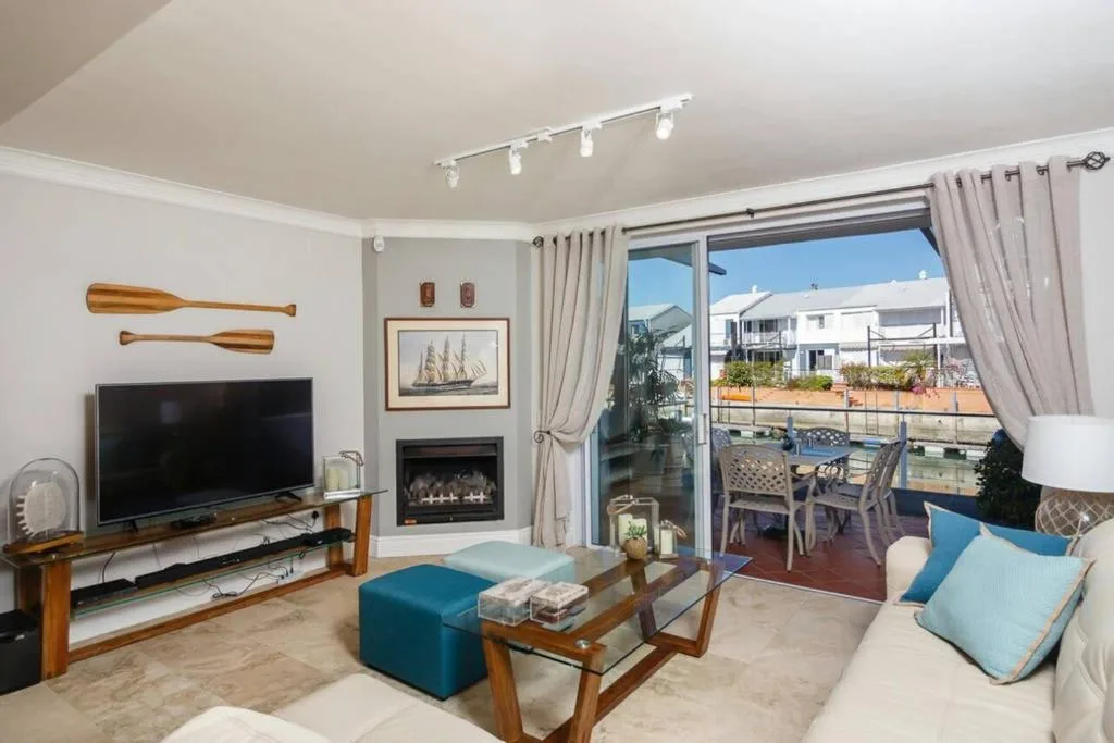Bright lounge with TV, fireplace, and water view through glass doors
