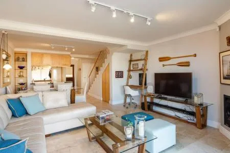 Open-plan living room with white sofa, television, and wooden staircase