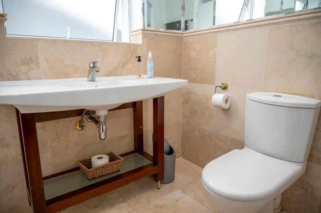 Modern bathroom with vanity sink, toilet, and travertine tile walls