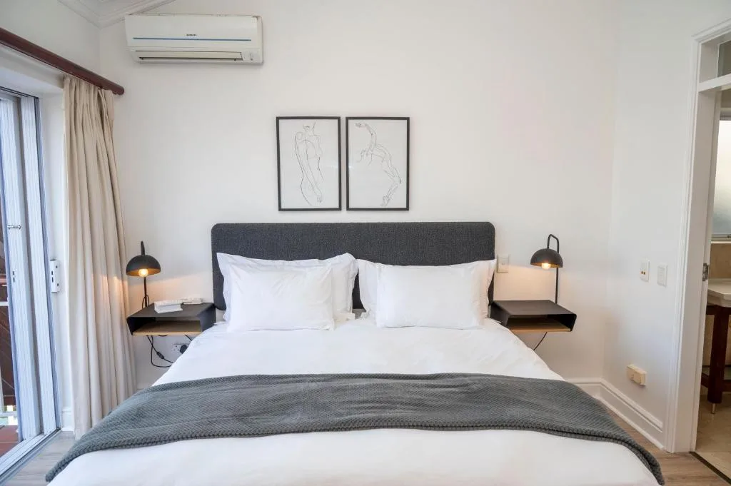 Modern bedroom with grey upholstered bed, white pillows, and pendant lamps