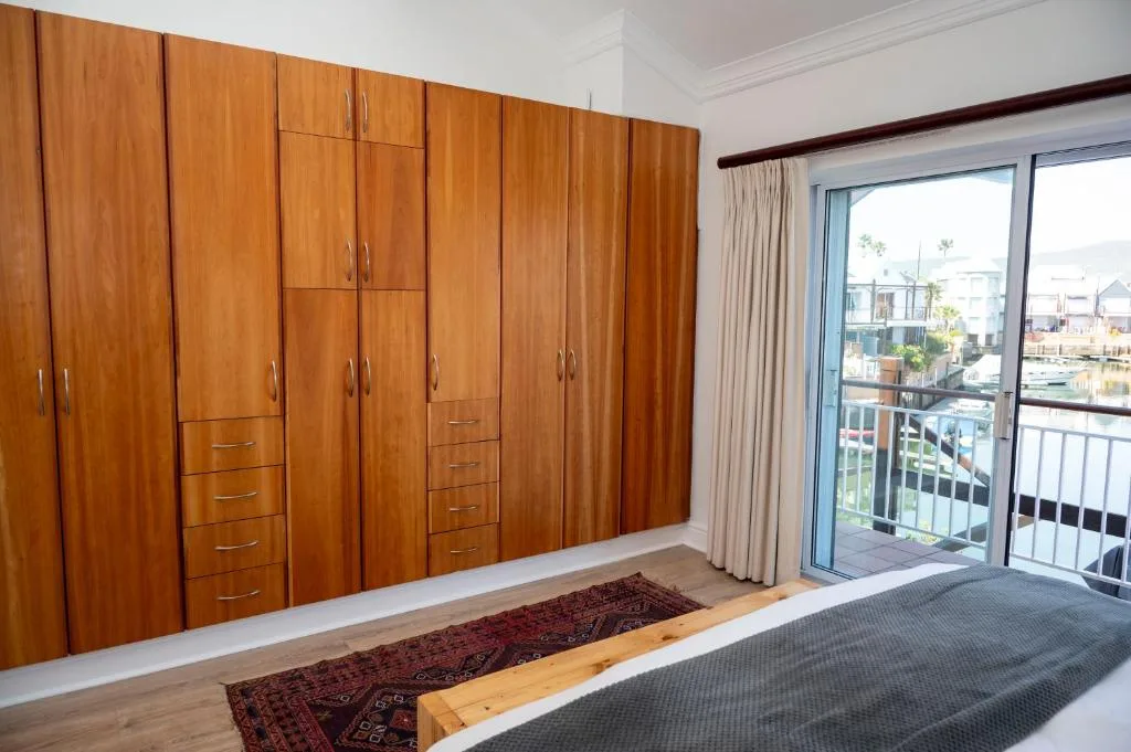 Spacious bedroom with wooden built-in wardrobes and glass door to waterfront deck