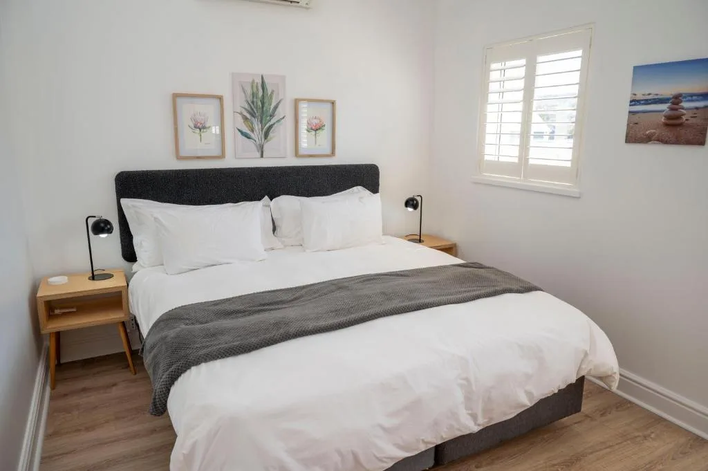 Bright bedroom with queen bed, white linens, and botanical wall art