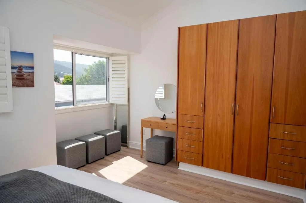 Bright bedroom with wooden wardrobe, vanity, and mountain views through window