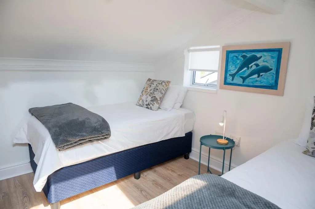 Bright bedroom with white bedding, navy base, and ocean-themed whale artwork