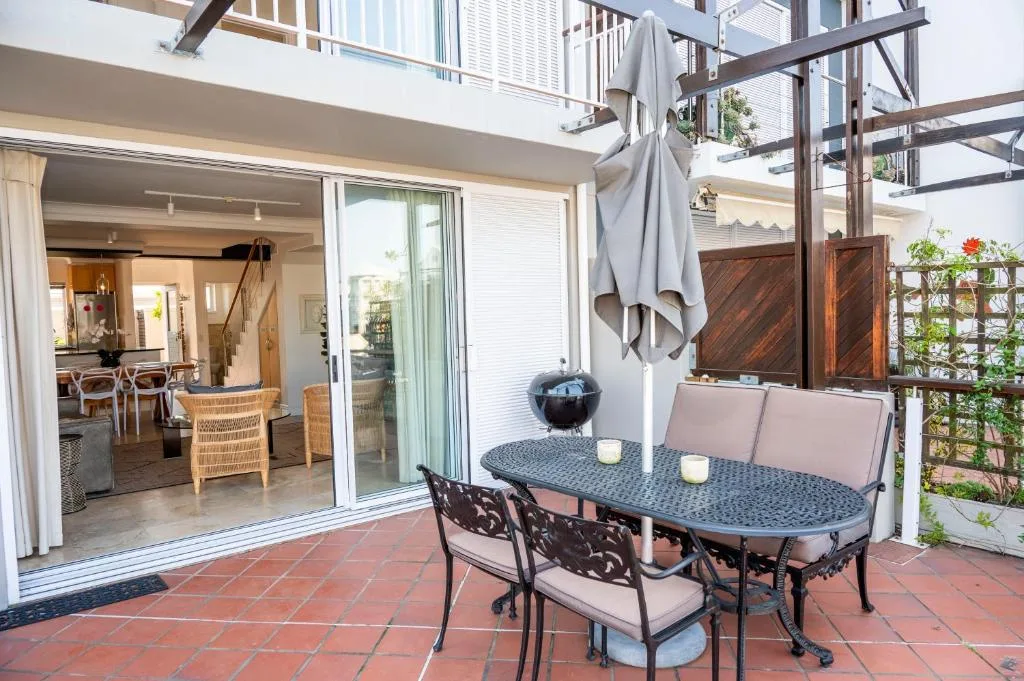 Outdoor patio with dining table, chairs, and views of the property's interior spaces