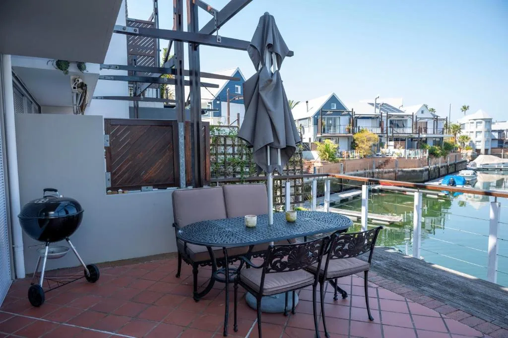 Waterfront deck with dining table, umbrella, and canal views