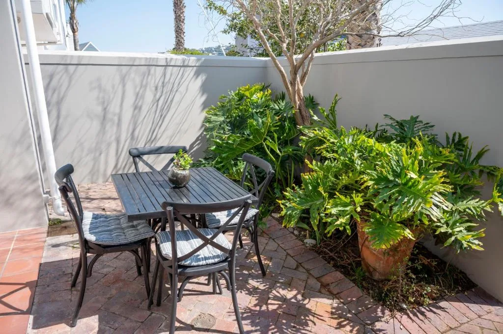 Outdoor patio with round table, chairs, and lush green landscaping