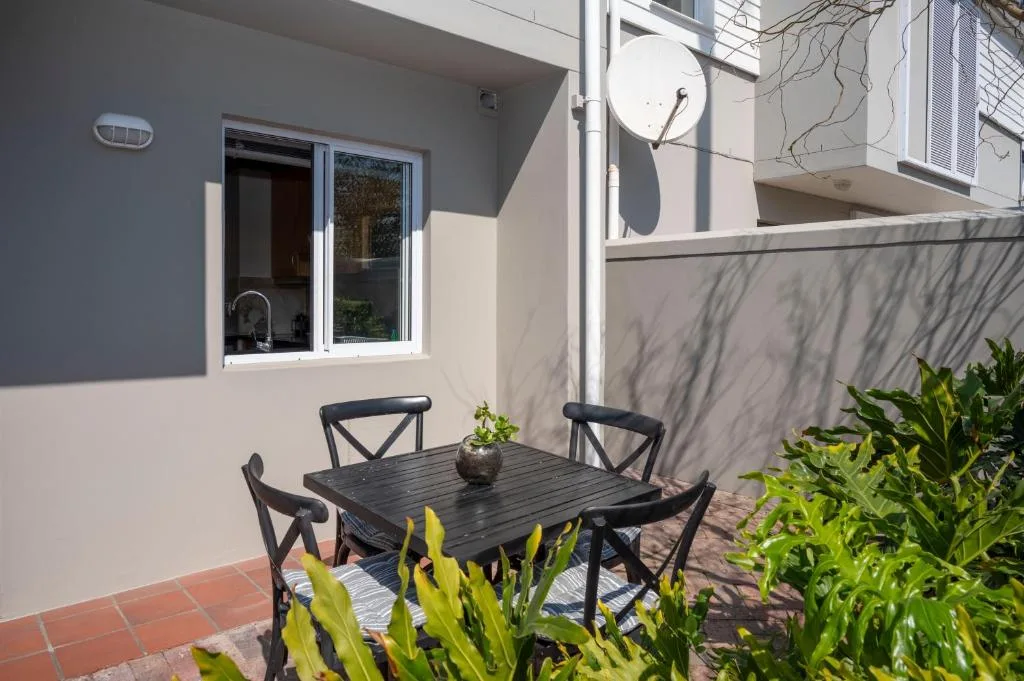Outdoor patio with black dining table, chairs, and potted plants