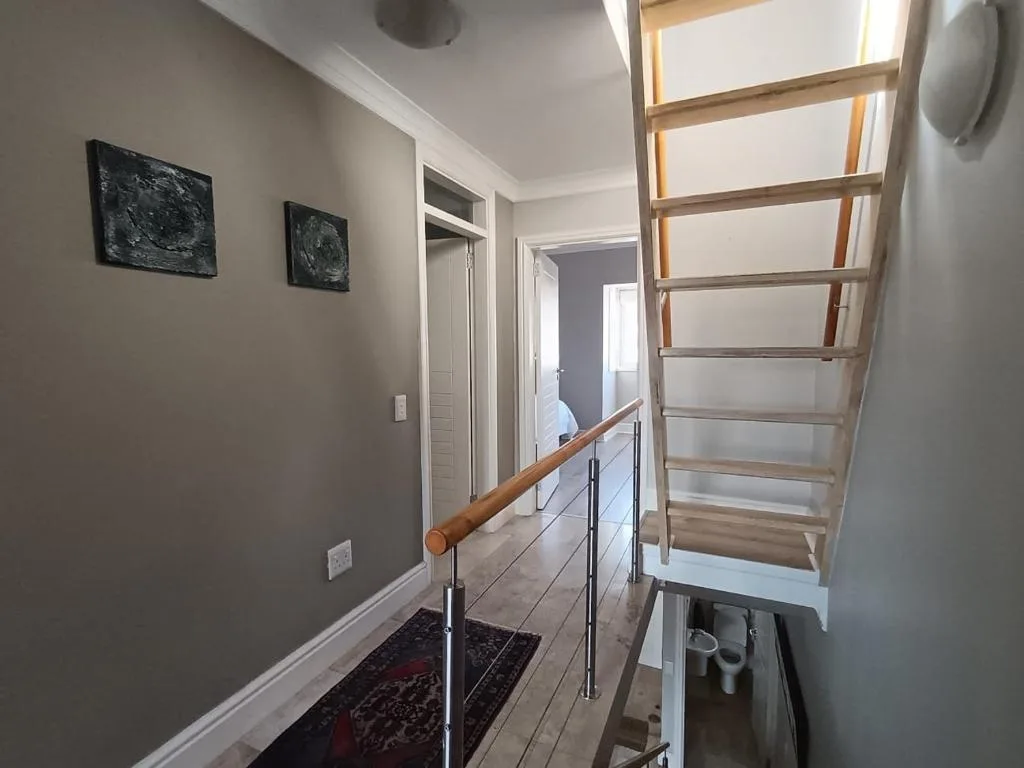 Modern interior hallway with wooden staircase and contemporary artwork on walls