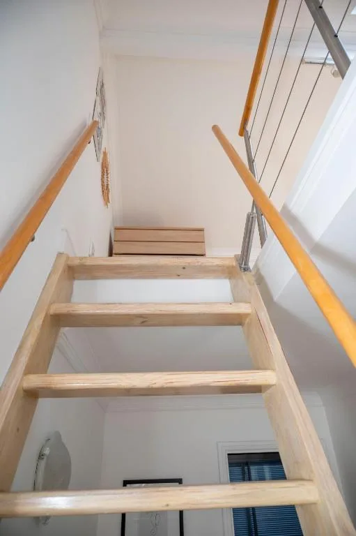 Wooden staircase with handrails viewed from below, bright interior